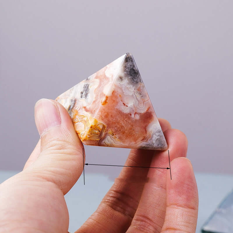 Hand holding a natural crystal stone pyramid ornament, perfect for meditation and mindfulness as an energy generator.