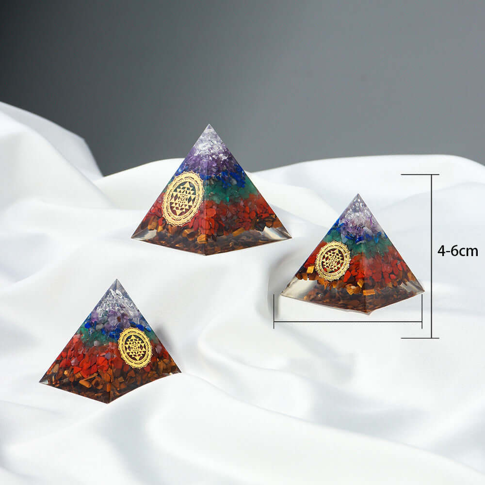 Decorative crystal stone pyramids for healing and energy, in various sizes, featuring a modern geometric design on a white fabric background.